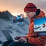 Un homme en montagne utilise un ordinateur avec des interfaces holographiques de montage et compression vidéo.