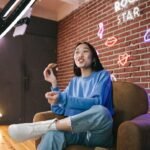 L’influenceuse filme une vidéo dans un studio coloré, mangeant une pizza devant une caméra professionnelle.